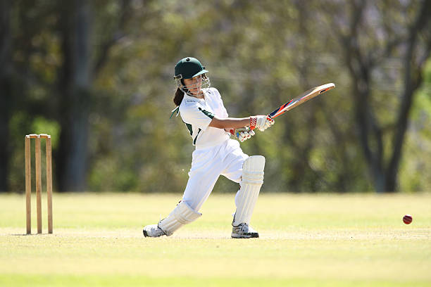 Young girl full whites mein elegant cover drive maarti, green helmet ke saath red ball pe - girls cricket academy amethi