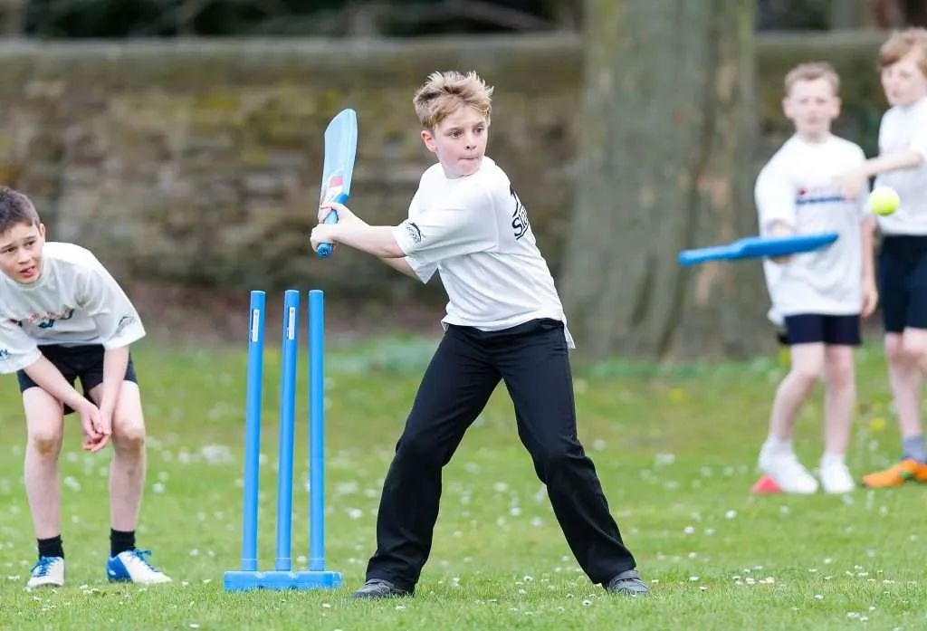 Young kid plastic bat se kwik cricket khelta, blue stumps ke saamne stance mein, school ground pe